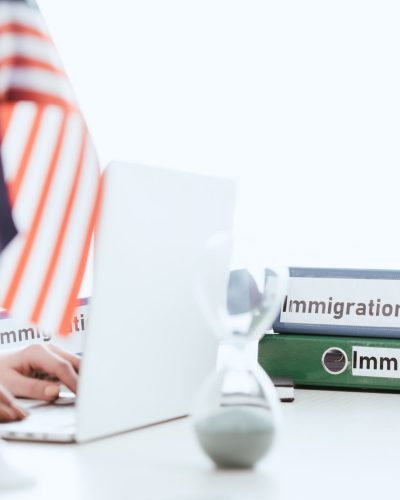 selective focus of woman typing on laptop near hourglass and american flag